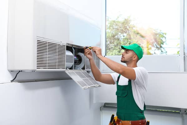 A technician installing the indoor unit of an HVAC system