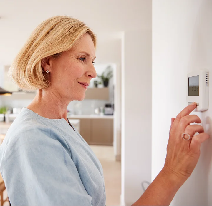 A woman adjusts the thermostat on a hot summer day
