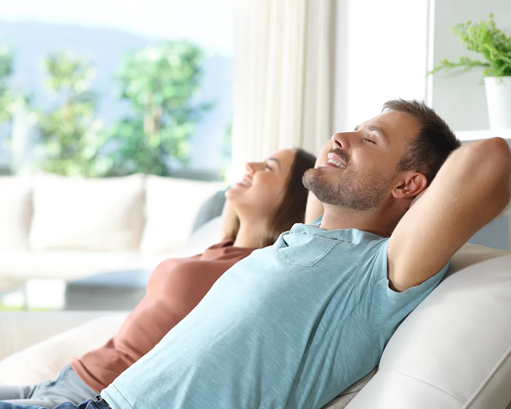 A man and woman relax in a cool air conditioned home